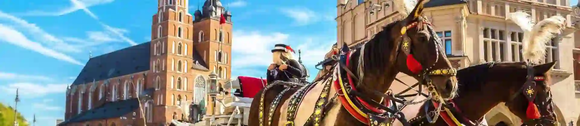 Traditional horse and carriage in Kraków, Poland, standing near St Mary’s Church in the Market Square, with the church’s gothic towers and surrounding historic buildings visible