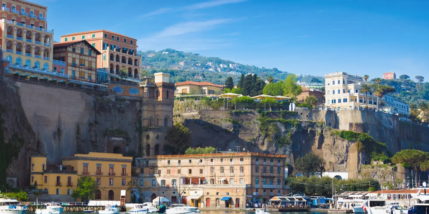 A sunny day in Sorrento, Italy, with multicoloured luxury hotels on the cliffs above a peaceful marina