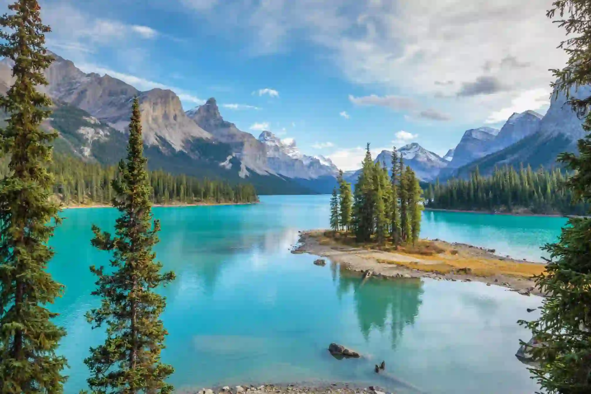 Scenic view of Spirit Island on Maligne Lake in Jasper National Park, Canada, surrounded by turquoise water, pine trees, and snow-capped mountains