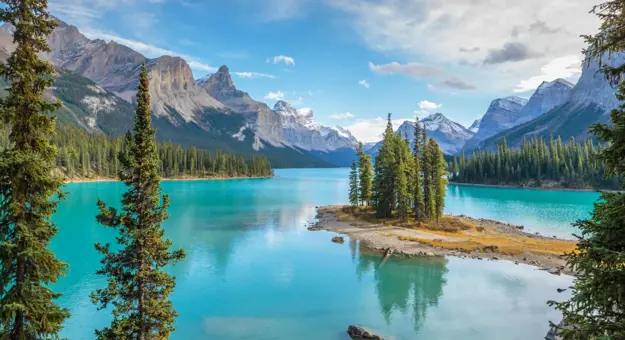 Scenic view of Spirit Island on Maligne Lake in Jasper National Park, Canada, surrounded by turquoise water, pine trees, and snow-capped mountains