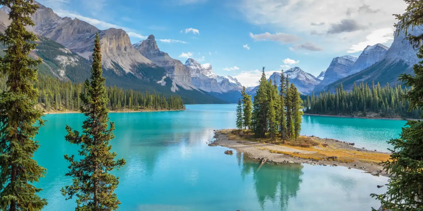 Scenic view of Spirit Island on Maligne Lake in Jasper National Park, Canada, surrounded by turquoise water, pine trees, and snow-capped mountains