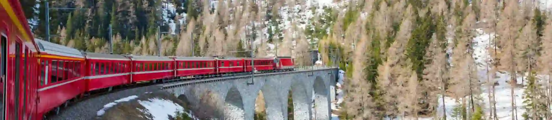 The Bernina Express train winding through snow-covered Alpine mountains on a scenic railway route