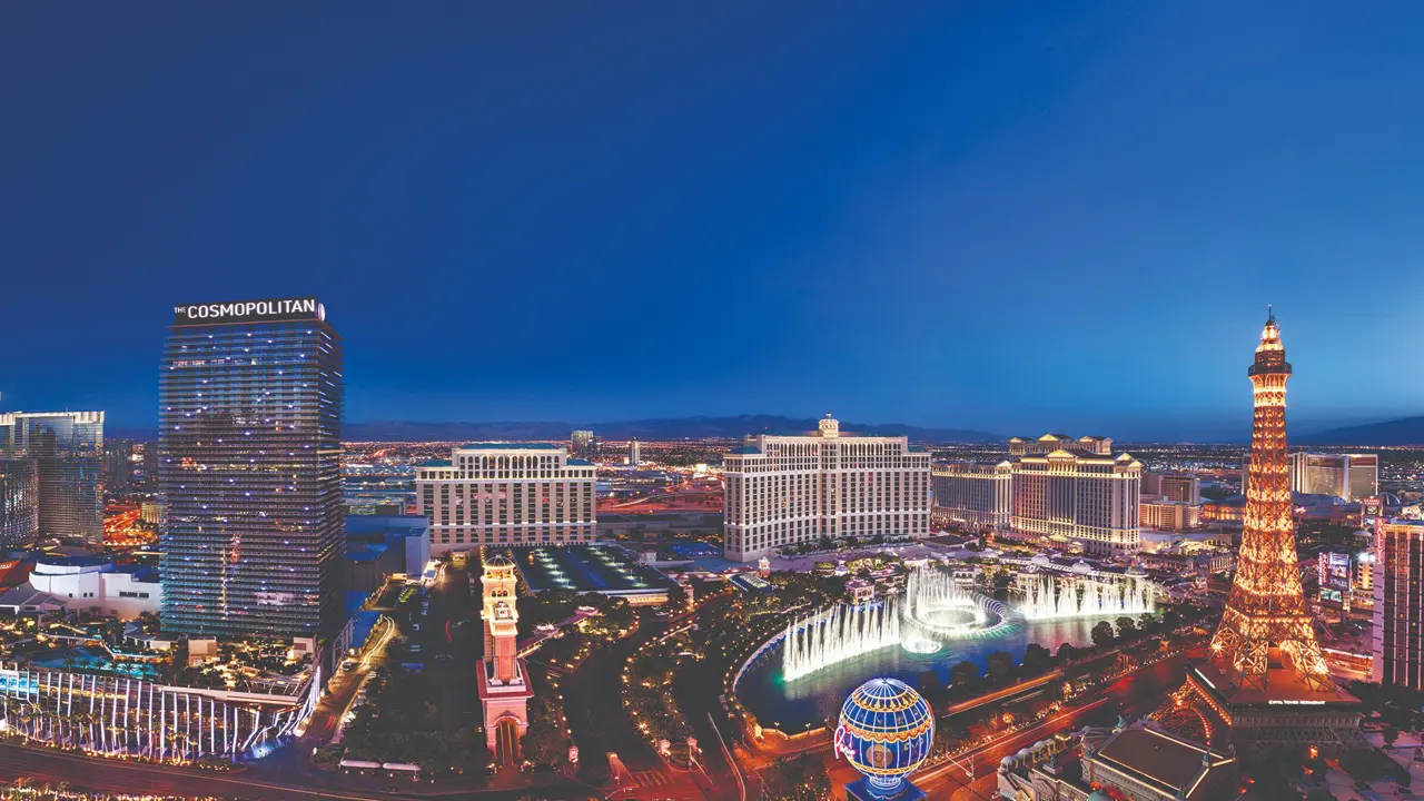 Aerial view of Las Vegas at night, with a dazzling display of colourful neon lights, illuminated streets, and iconic casinos glowing against the dark sky