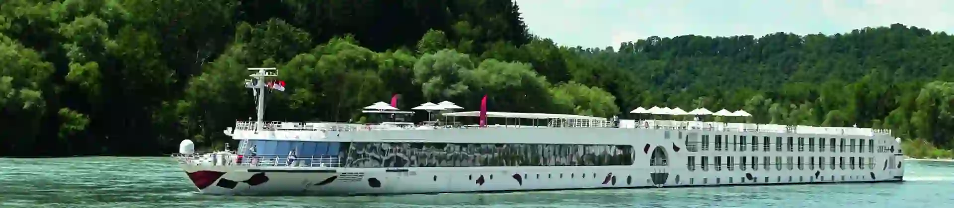 An A-ROSA river cruise ship sailing down a river with trees in the background