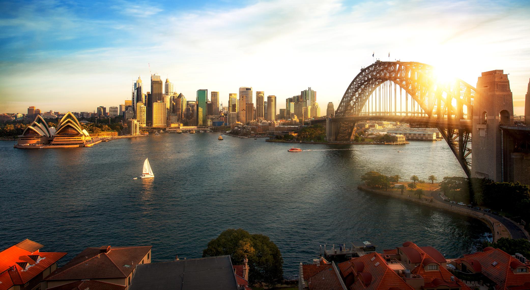 The Sydney Opera House beside Sydney Harbour with the city skyline in the background.