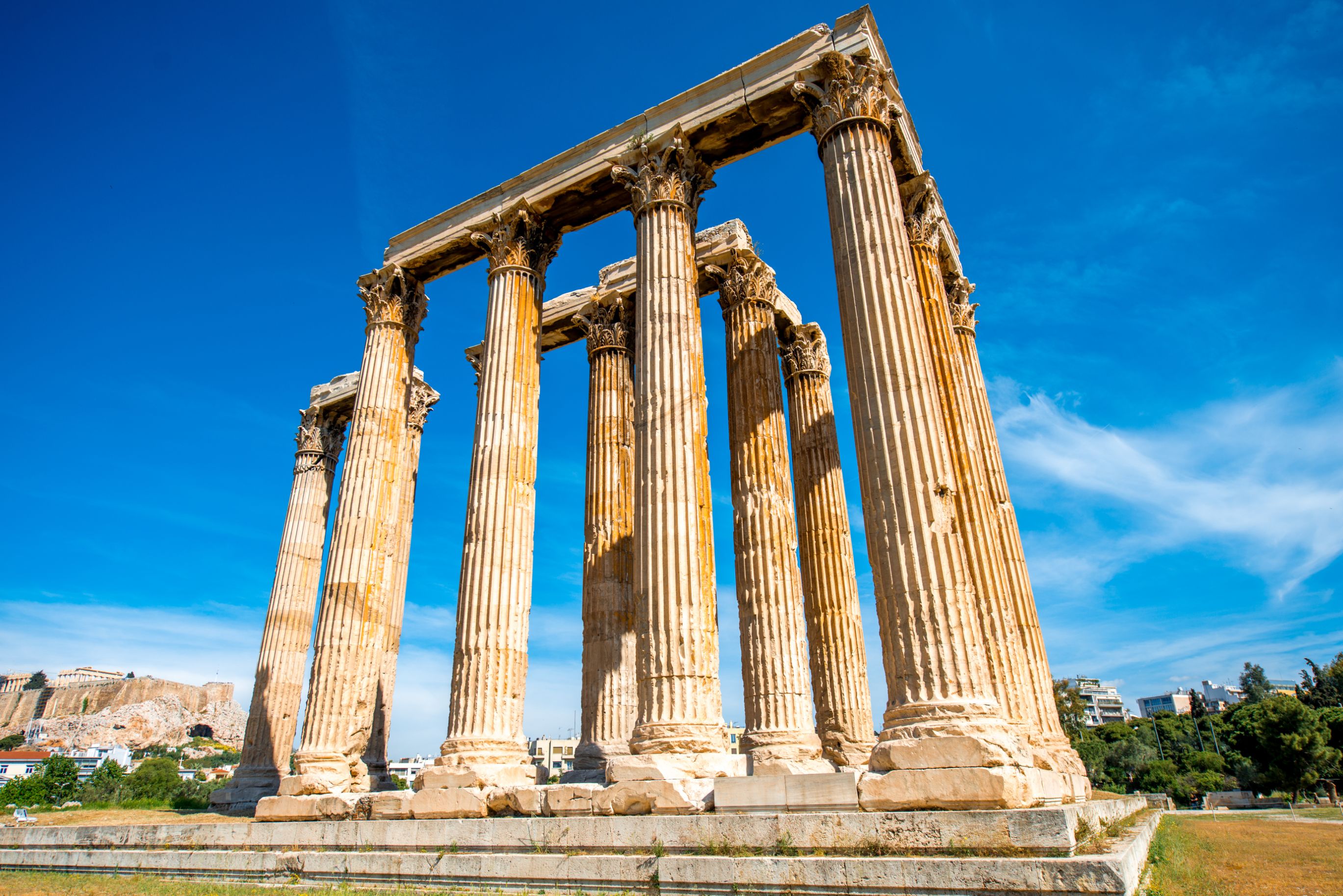Low angle shot of temple ruins, with pillars. Blue sky behind