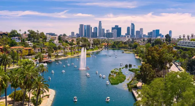 View of Los Angeles with a lake in the foreground, boats on the water, and the city skyline in the background