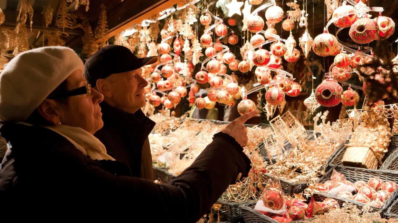 Mature couple looking at Christmas baubles being sold at a Christmas Market stall