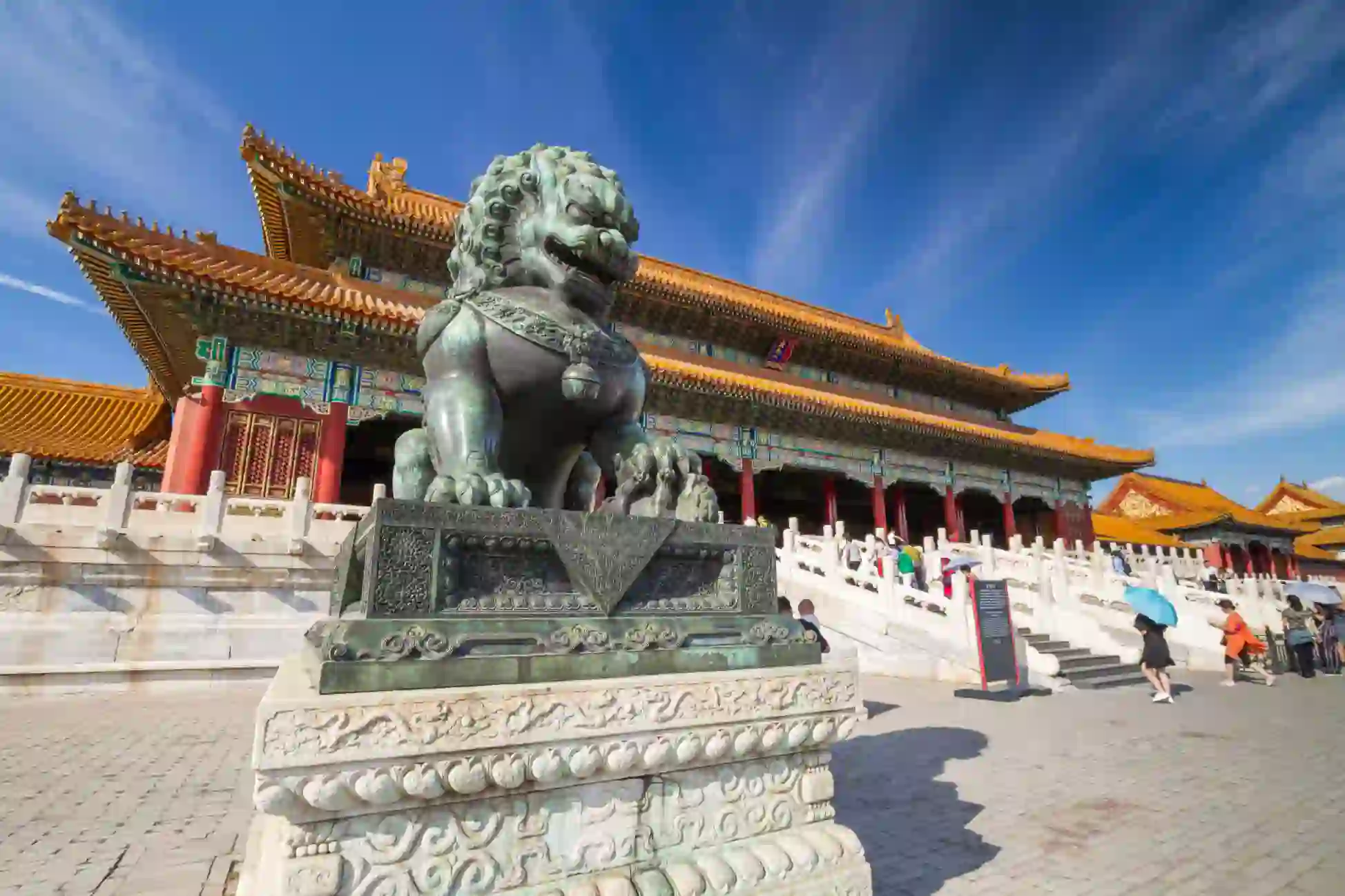 Bronze guardian lion outside ornate palace buildings in the Forbidden City, Beijing, China