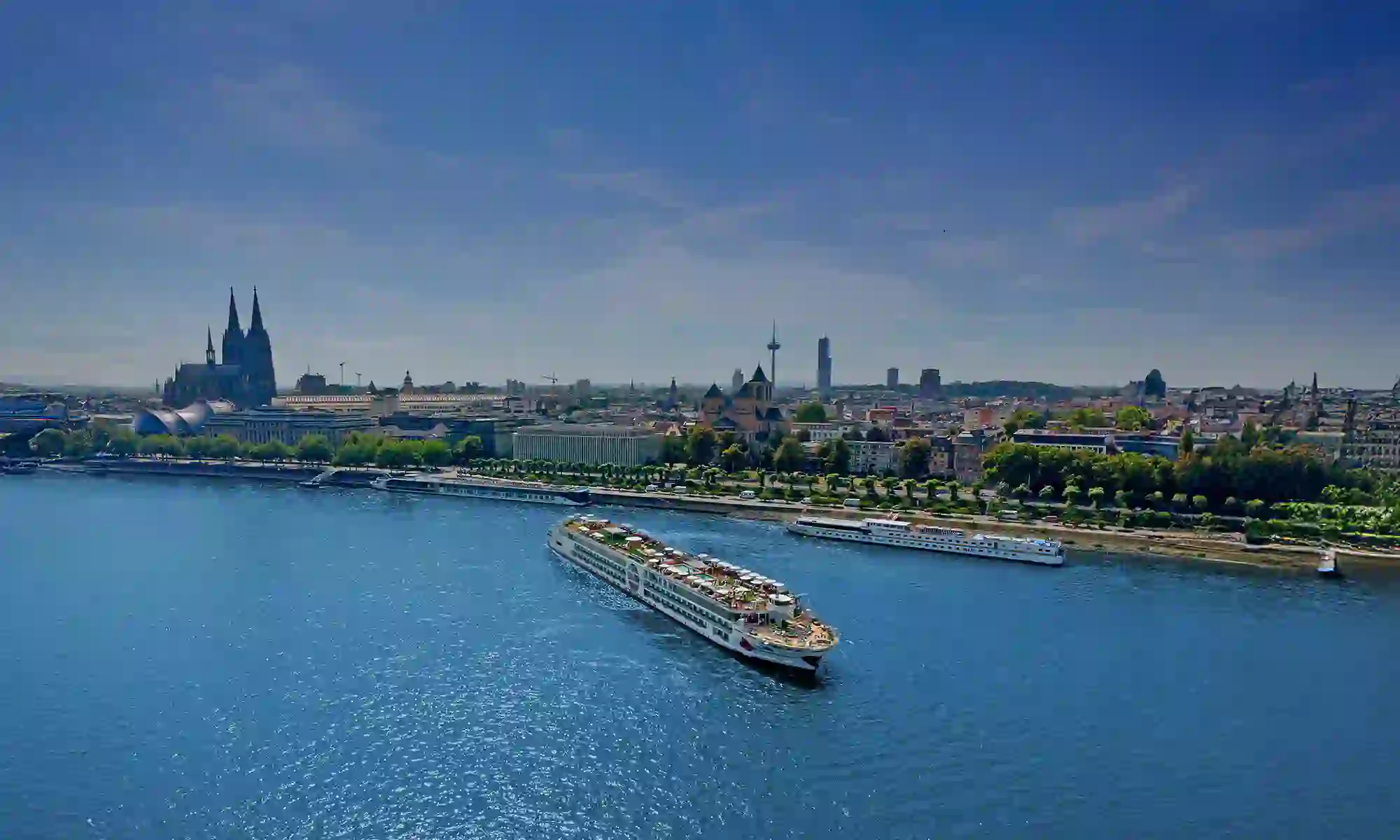 A-ROSA river cruise ship sailing on the Rhine River with Cologne Cathedral and city skyline in the background
