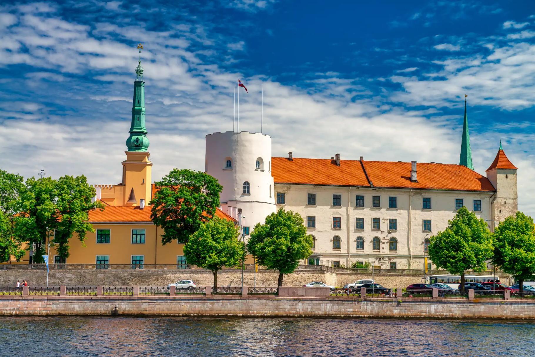 Historic Riga Castle with red rooftops and spires along the Daugava River
