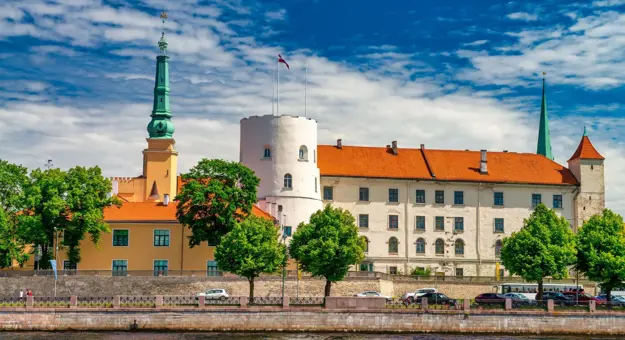 Historic Riga Castle with red rooftops and spires along the Daugava River