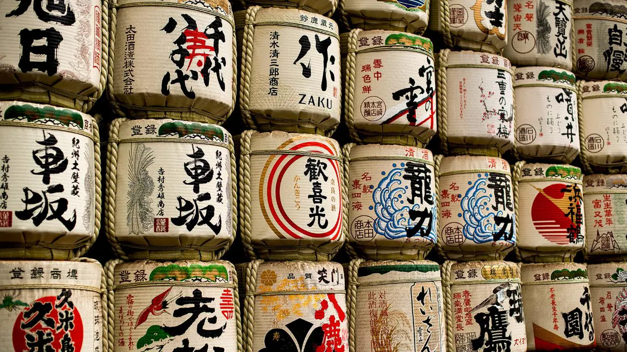 Close-up view of vividly painted sake barrels wrapped in straw, part of a traditional offering at Meiji Shrine in Tokyo
