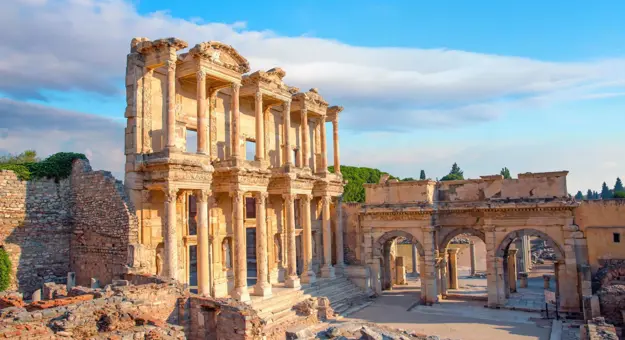 Ancient ruins of the Library of Celsus in Ephesus, Turkey, with a clear sky and warm sunlight highlighting the detailed stone architecture