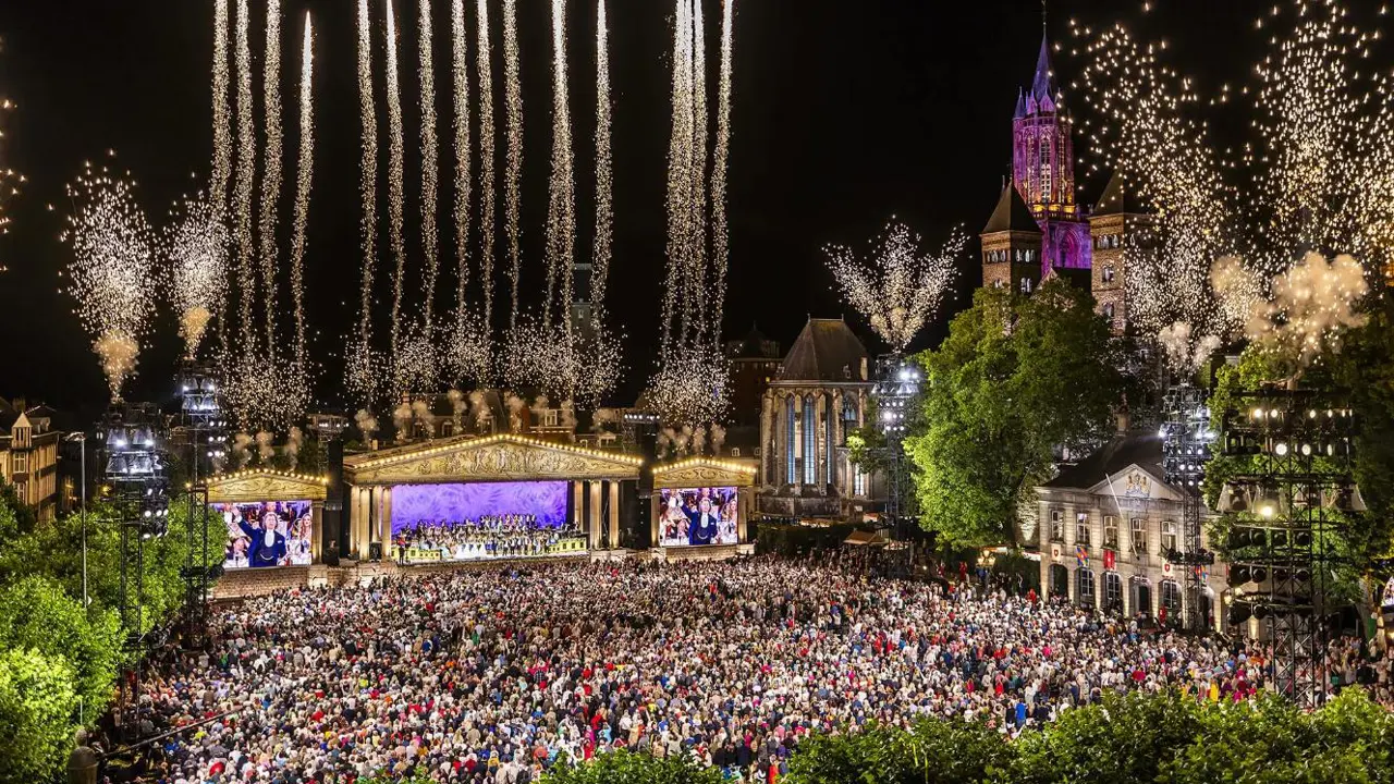 André Rieu performing in Maastricht’s Vrijthof Square, with his orchestra on stage and colourful fireworks lighting up the night sky