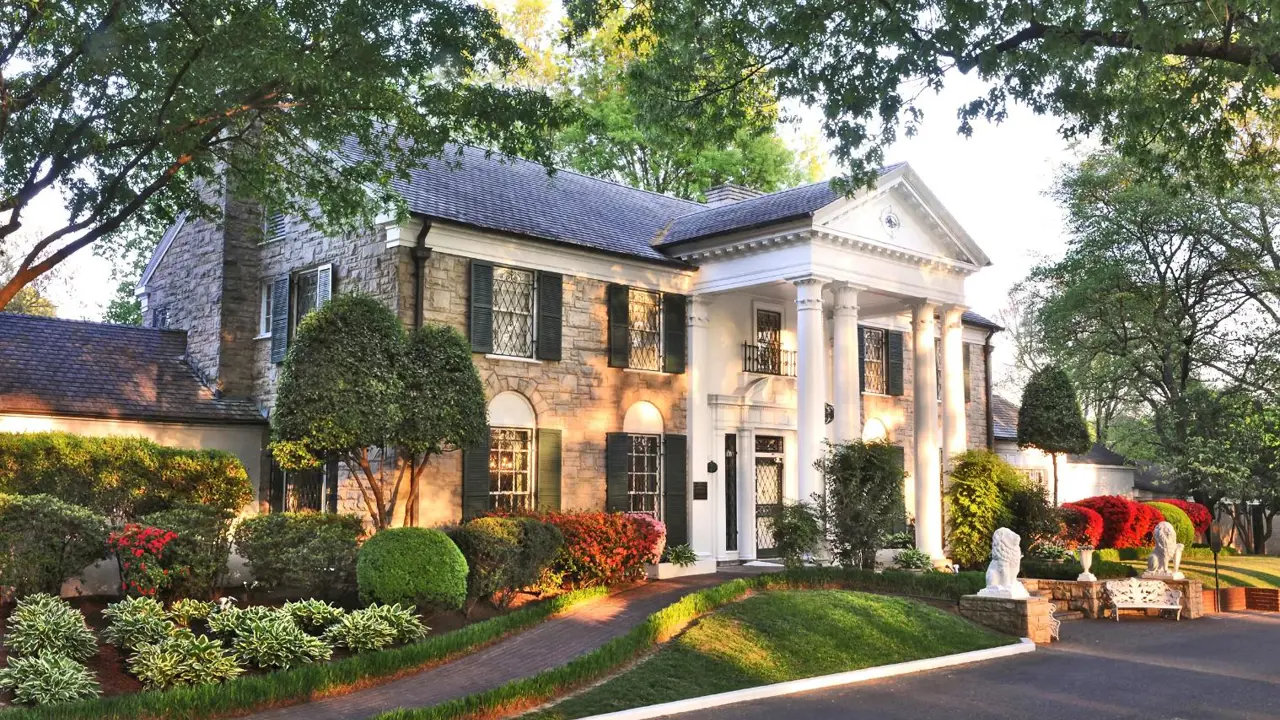 Graceland mansion in Memphis, Tennessee, the former home of Elvis Presley, featuring a grand white-columned façade surrounded by well-kept lawns and tall trees