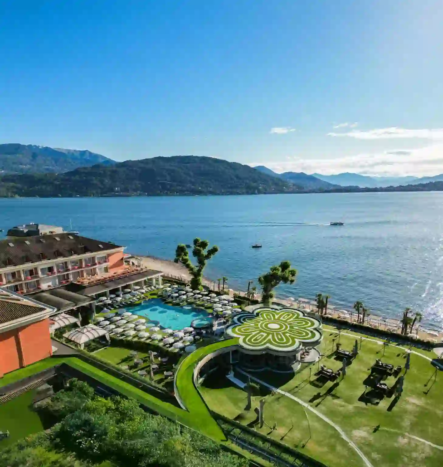Aerial view of the lakeside pool and gardens at Grand Hotel Dino in Baveno, with Lake Maggiore and mountains in the background