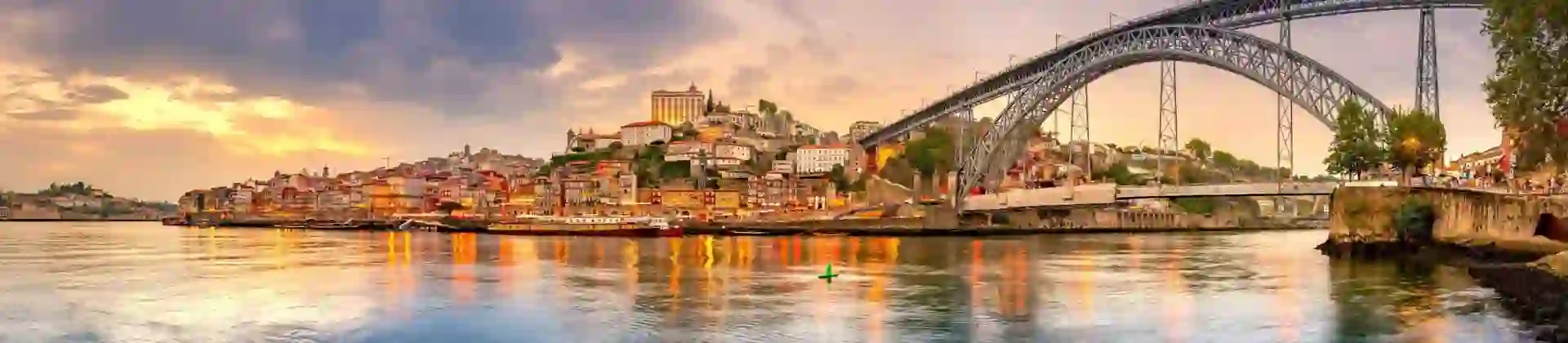 Picturesque view of Porto, Portugal, showing the Dom Luís I Bridge crossing the Douro River, with historic, colourful buildings along the riverbanks