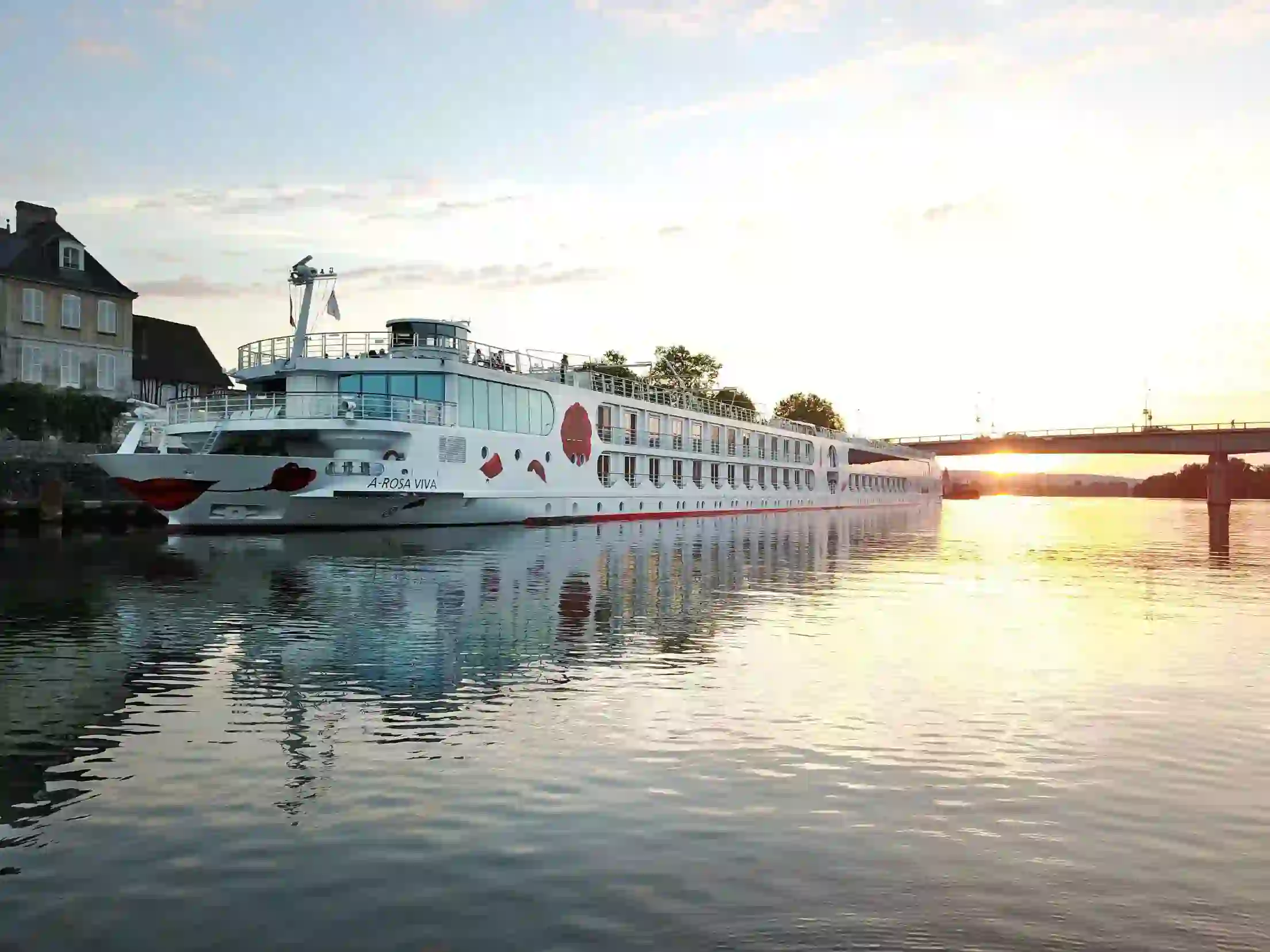 A-ROSA VIVA cruise ship on a calm city river at sunset, with a bridge in the background
