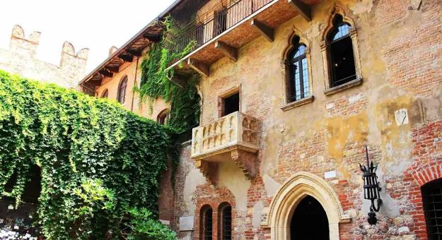 Juliet's Balcony on a brick and stucco building in Verona, Italy, with arched windows and doors, inspired by Shakespeare's Romeo and Juliet