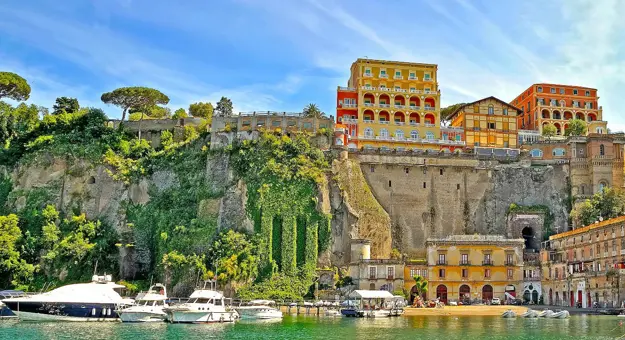 View of Sorrento from the water, with boats in the forefront and hotels and restaurants on the cliff top