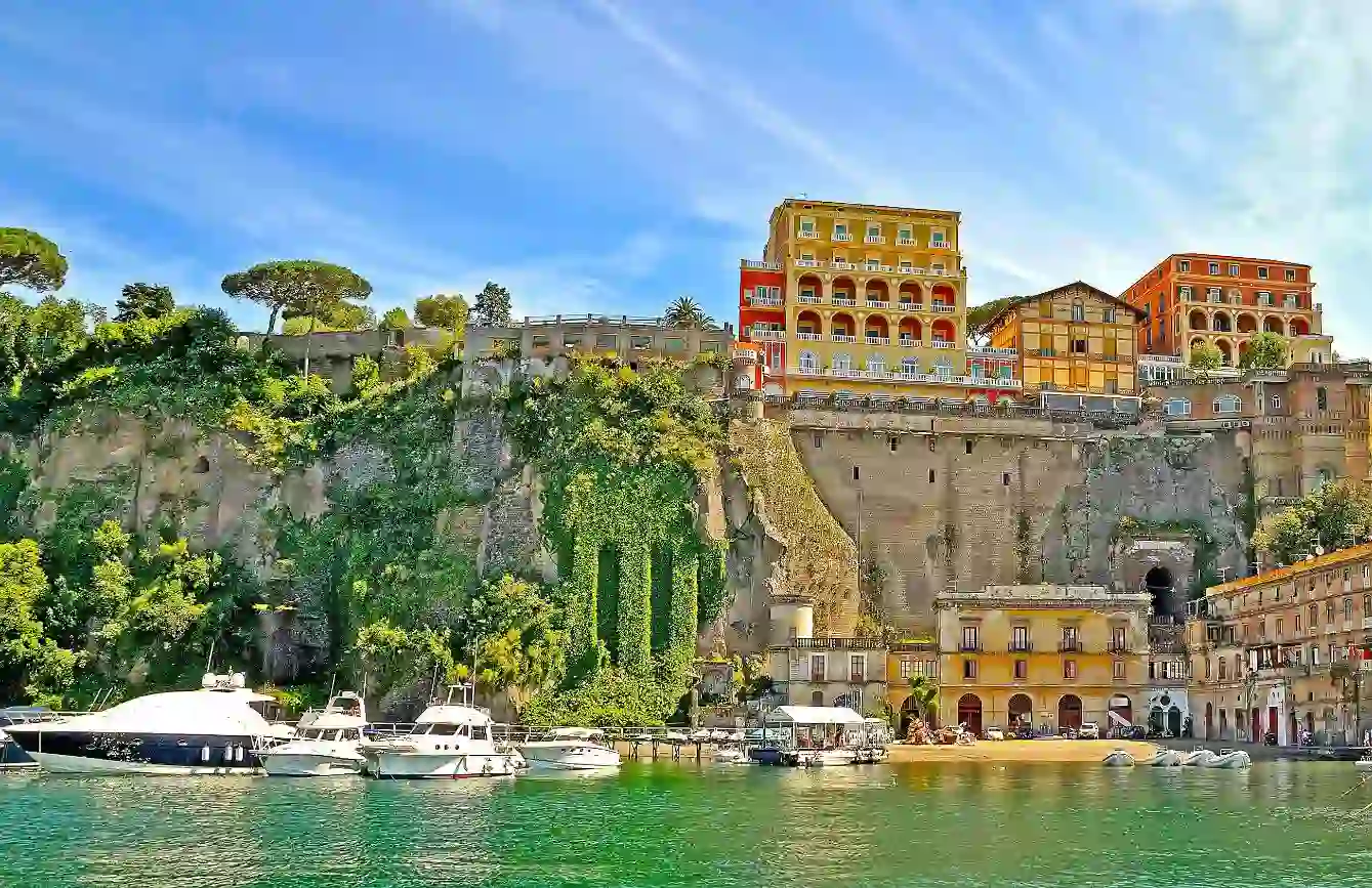 View of Sorrento from the water, with boats in the forefront and hotels and restaurants on the cliff top