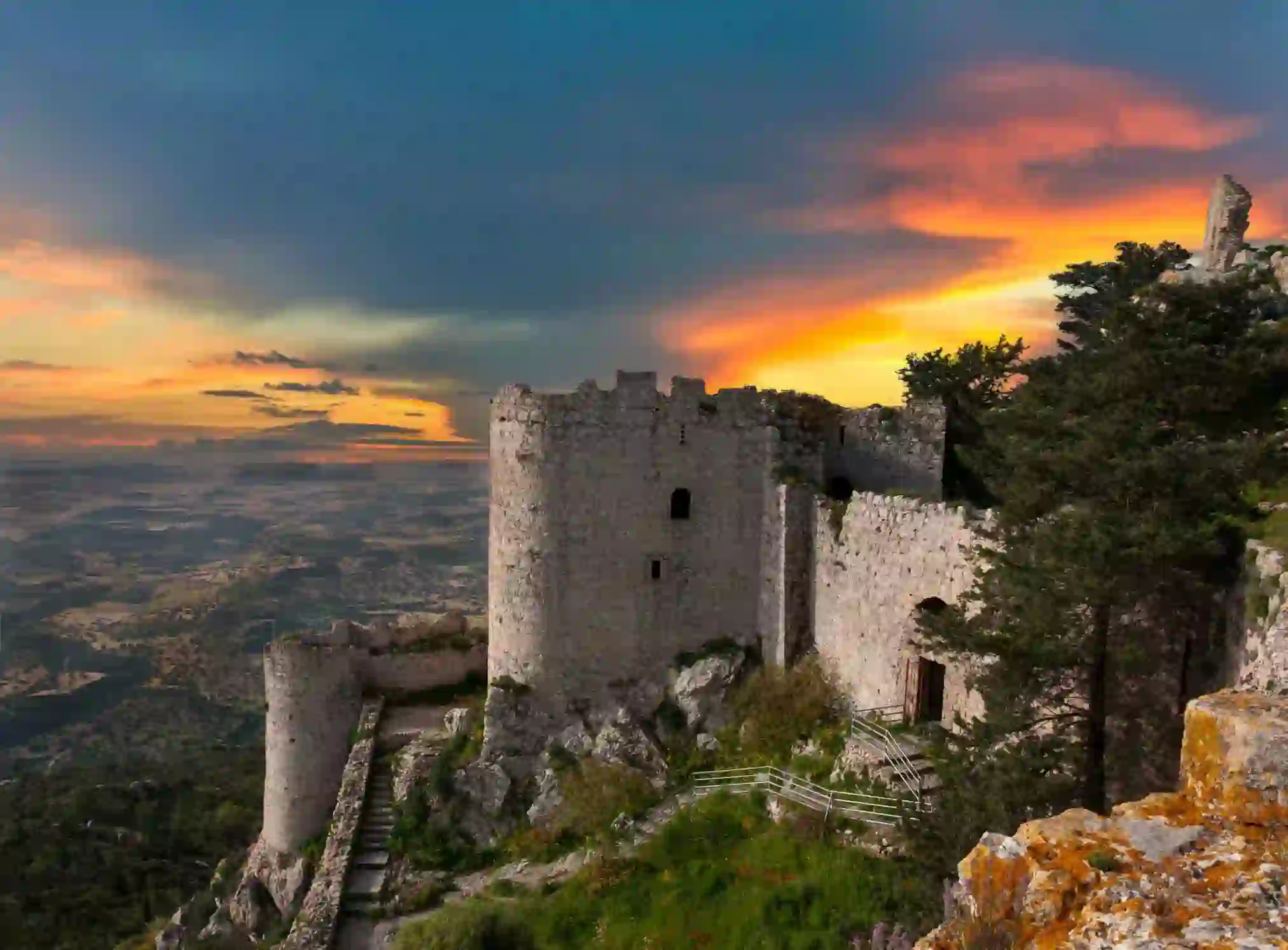 Ancient stone castle ruins on a hilltop overlooking the landscape of Northern Cyprus at sunset
