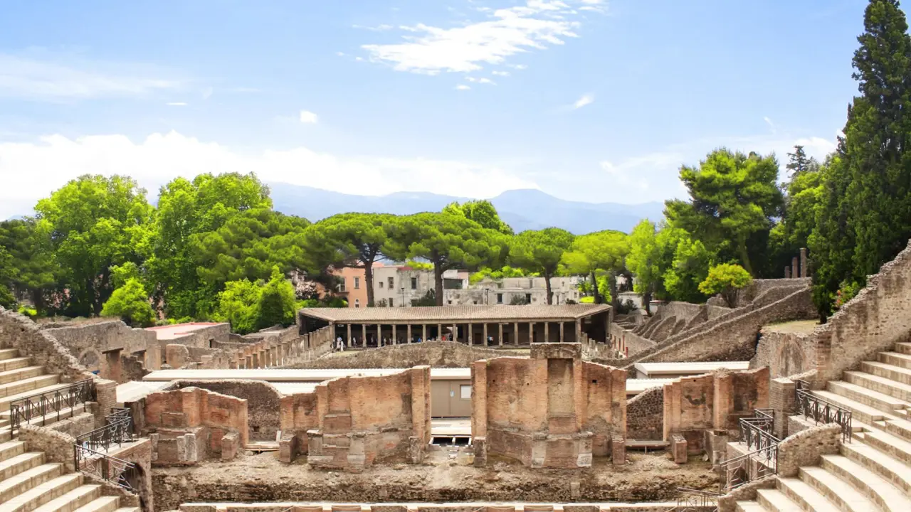 The theatre district in Pompeii with the ancient theatre in the foreground and the Quadriporticus - a large rectangular courtyard surrounded by covered walkways visible behind it