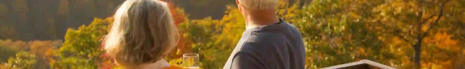A couple enjoying a glass of wine on a terrace overlooking rolling countryside and colourful trees in New England during autumn