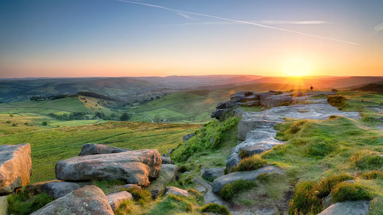 View of the Peak District at sunrise, with the sun creeping over the mountains
