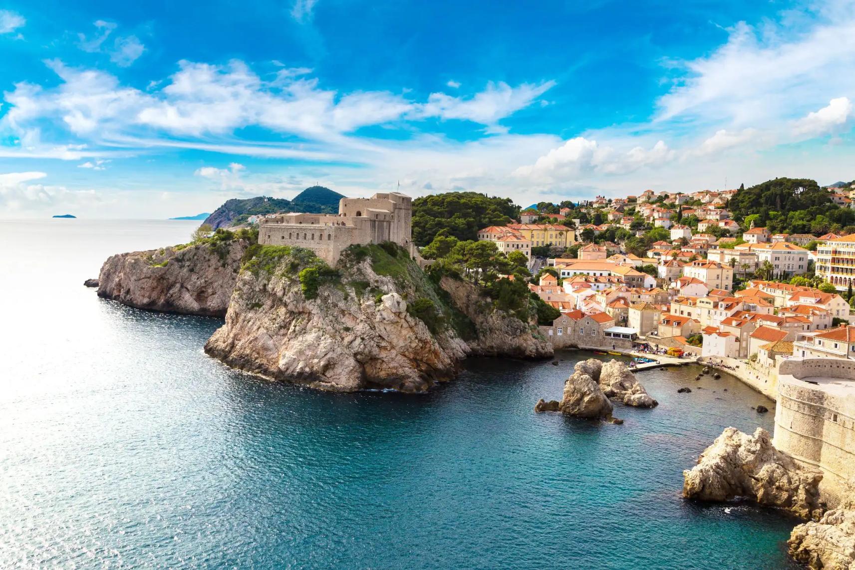 Panoramic view of the walled Old Town of Dubrovnik, Croatia, perched on a rocky coastline beside the blue waters of the Adriatic Sea
