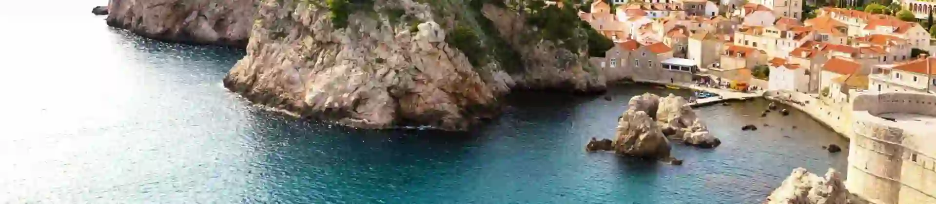 Panoramic view of the walled Old Town of Dubrovnik, Croatia, perched on a rocky coastline beside the blue waters of the Adriatic Sea