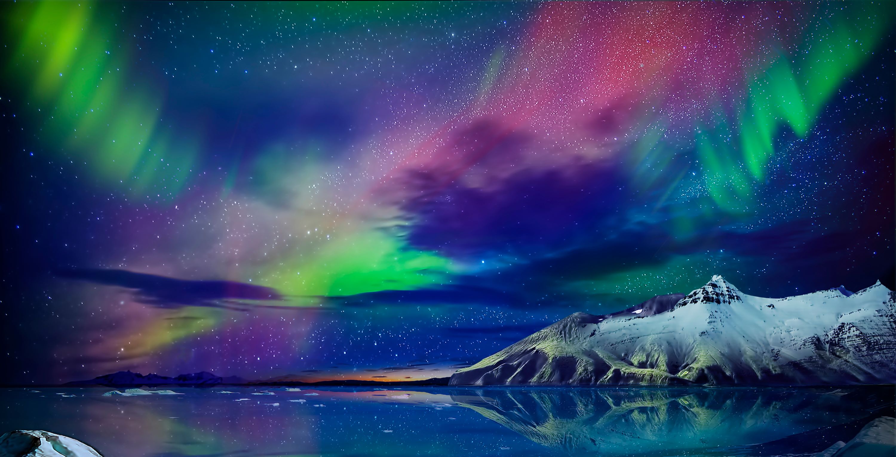 Starry sky with green, purple and blue Northern Lights. Below, a lake and a snowy mountain
