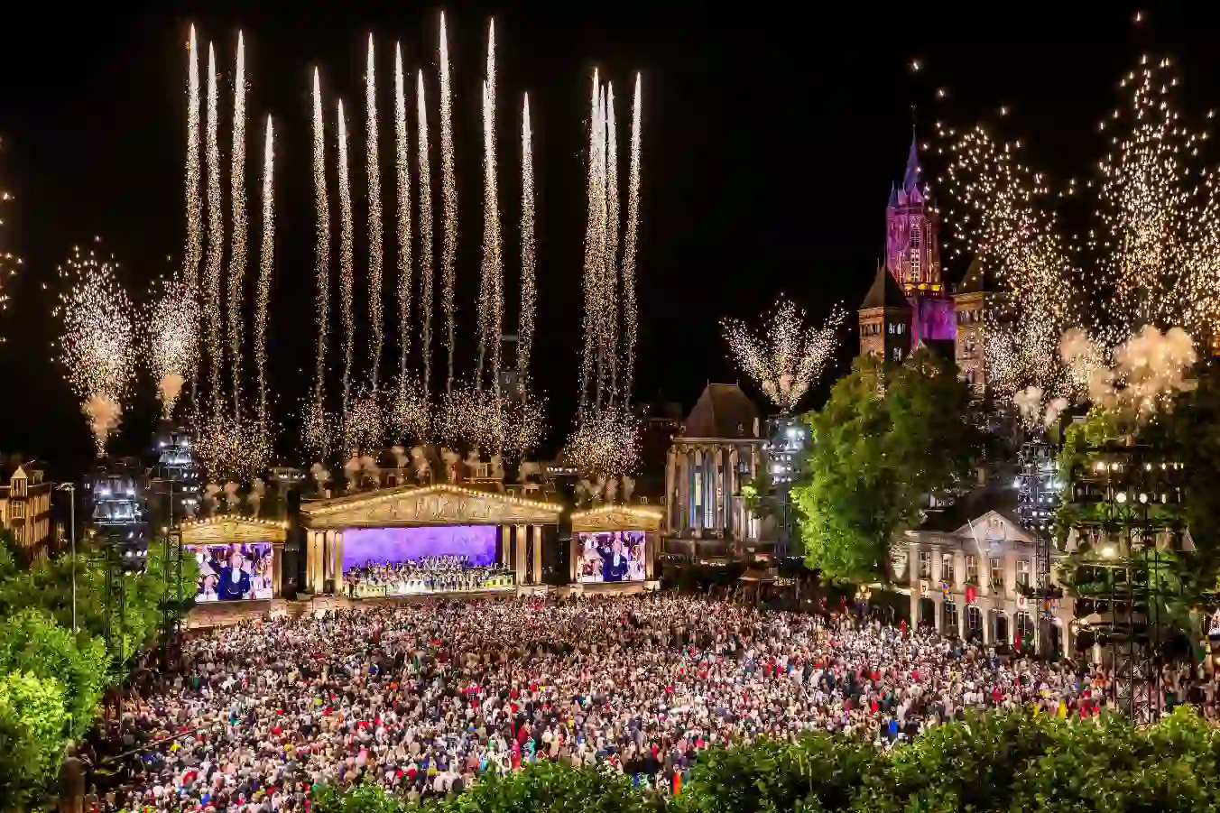 André Rieu performing live in Maastricht's Vrijthof square whilst fireworks light up the sky above the stage