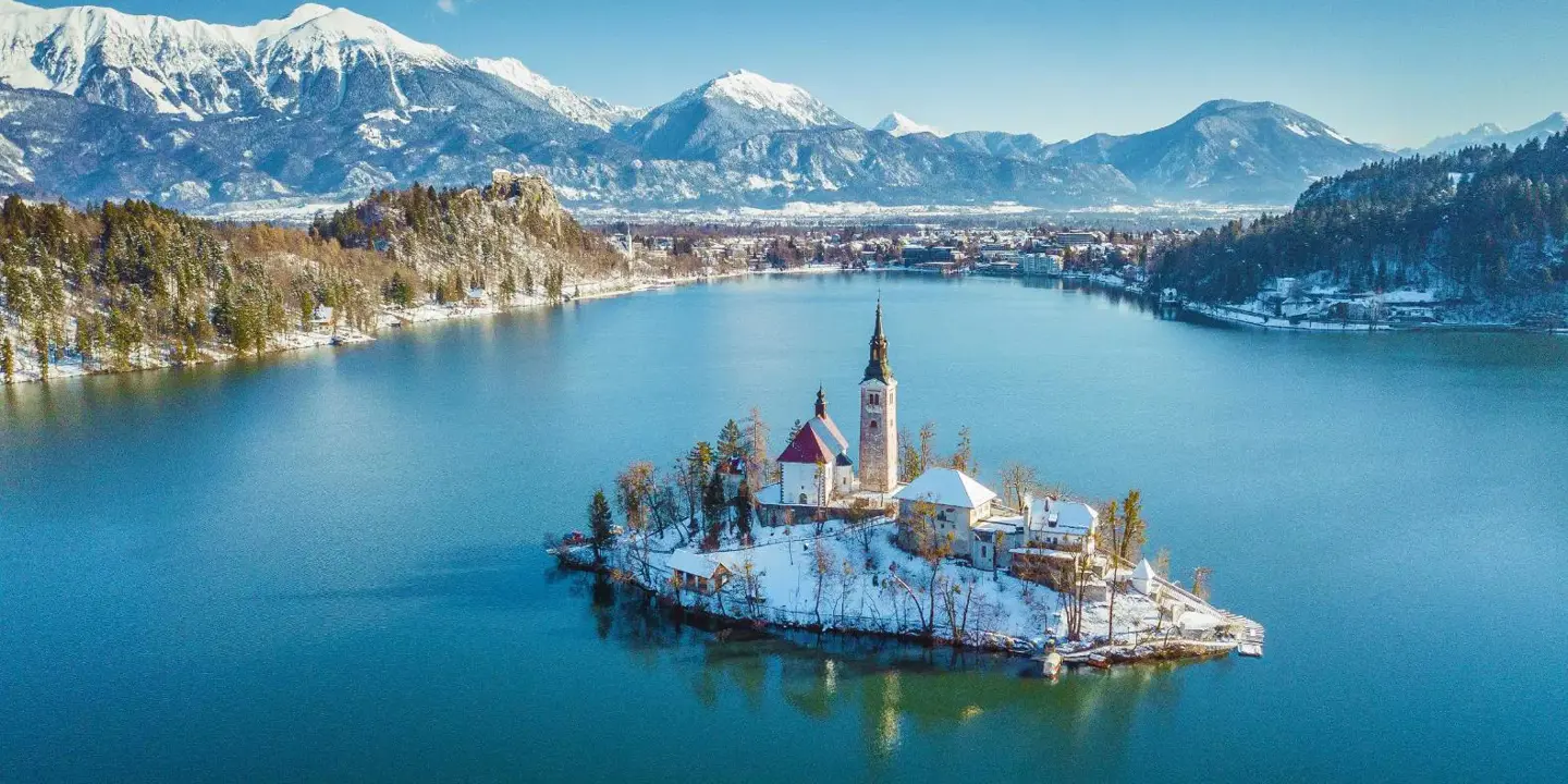 Lake Bled in winter with its island church in the centre and frosty mountains in the background