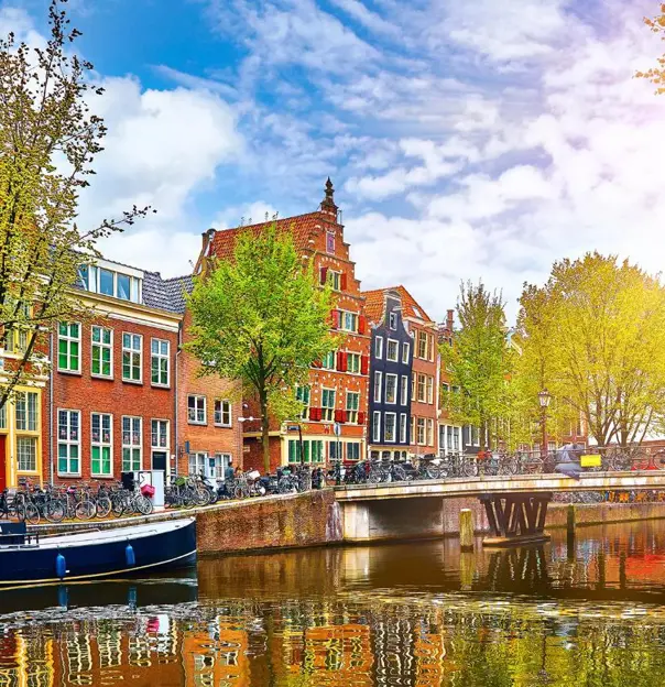 Scenic view of a canal in Amsterdam, Netherlands, with traditional Dutch buildings lining both sides
